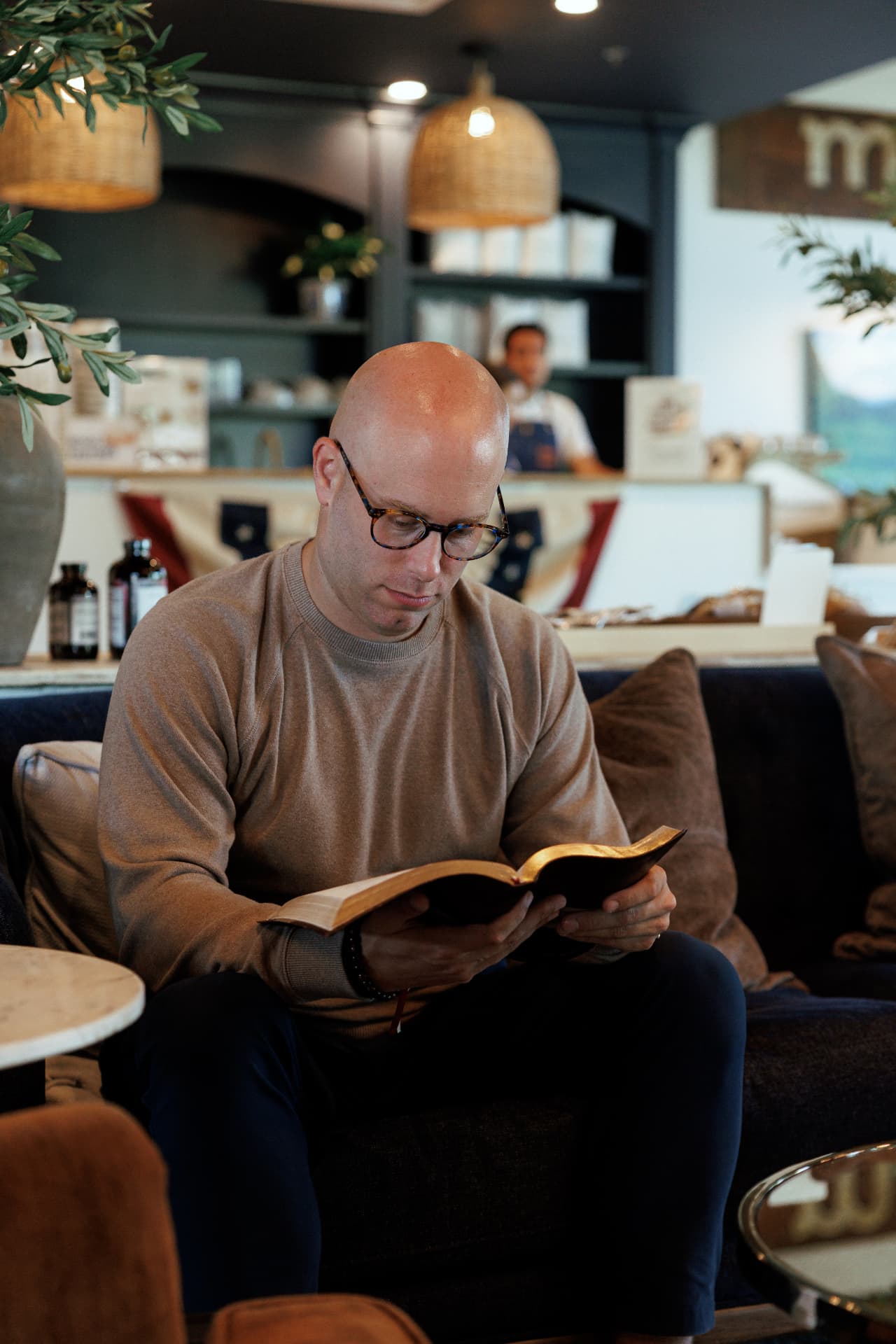 Zach Barnett reading a book on a cafe sofa