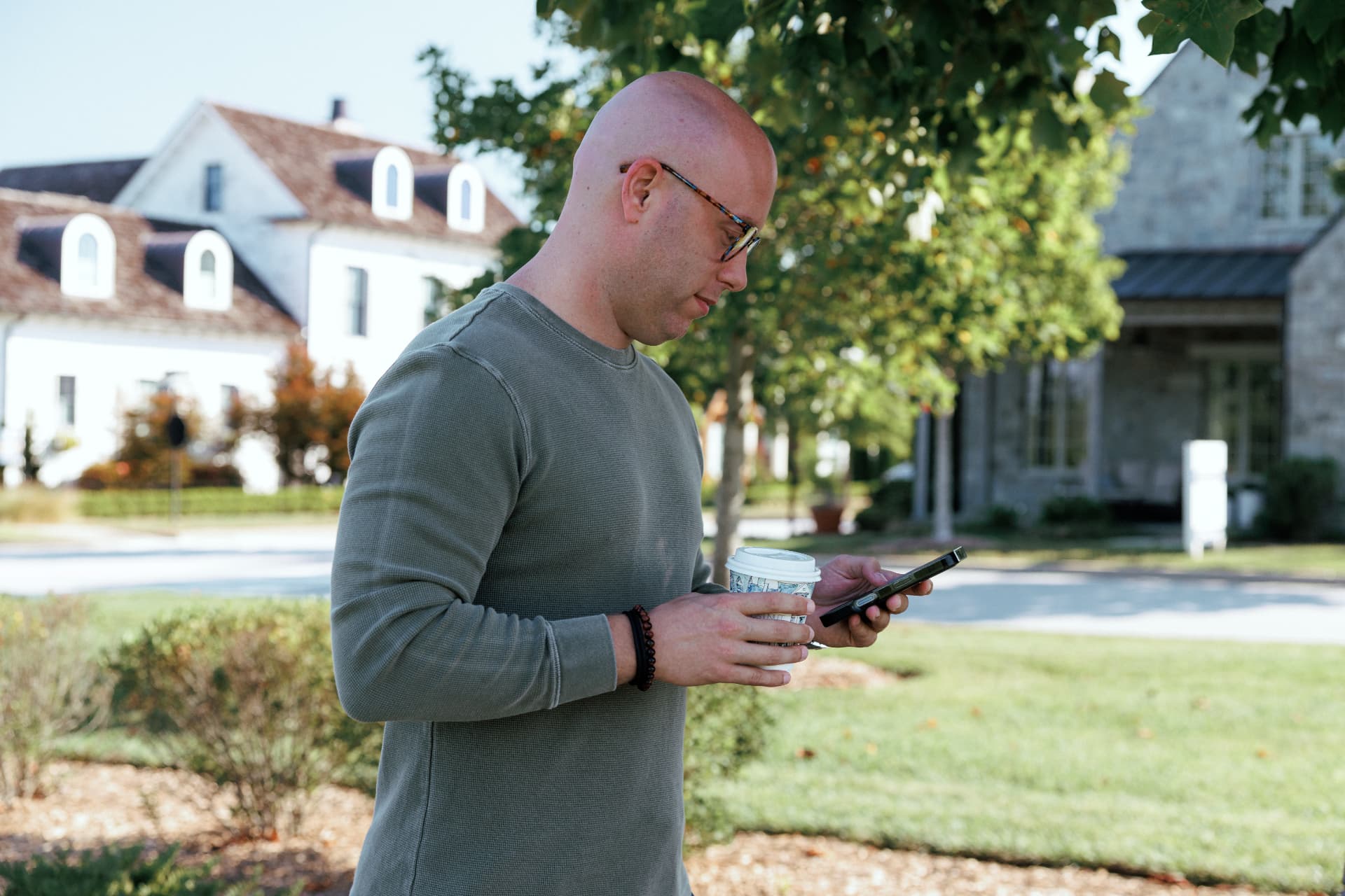 Zach Barnett with coffee, checking his phone outdoors